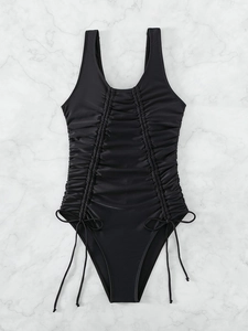 Elegant black one-piece swimsuit with front ruching and side drawstring details on marble