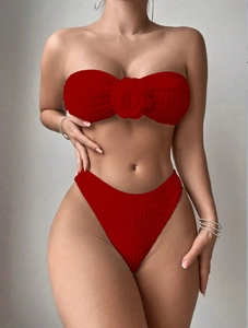 Détail du bikini rouge côtelé avec accent floral 3D et tissu texturé à taille haute