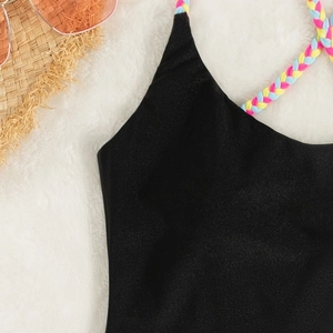 Close-up of black swimsuit with colorful braided rope straps and beach accessories