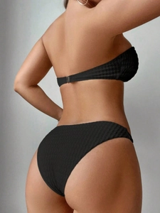 Détail du tissu noir à texture gaufrée sur un bikini deux pièces avec fermoir métallique