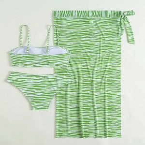Flat lay of a three-piece bikini set with green and white zebra print and mesh sarong