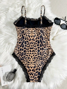 Flat lay of leopard print bodysuit featuring delicate black lace trim on white plush rug