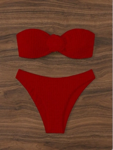 Détail macro du tissu rouge côtelé et du nœud décoratif sur ce bikini deux pièces chic