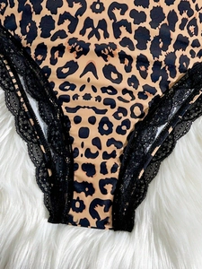 Close-up of leopard print bodysuit with black lace trim on a white plush background