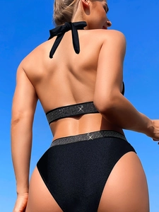 Sexy black halter neck bikini with rhinestone trim against a clear blue sky background