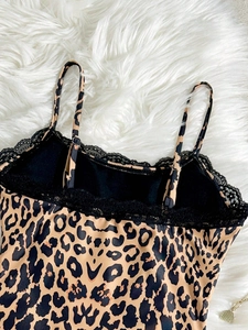 Detailed close-up of leopard print bodysuit with delicate black lace trim on plush background