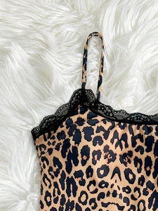 Close-up of leopard print bodysuit with black lace trim on a white plush background