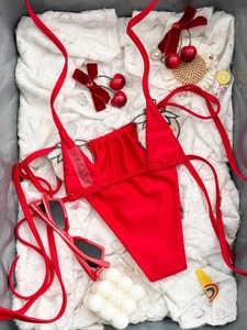 Dettaglio di un bikini rosso fragola con ricami di paillettes su pizzo bianco