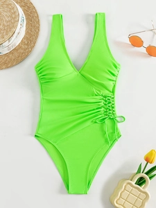 Flat lay of neon green one-piece swimsuit with V-neck, side ties and metallic rings