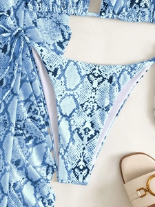 Flachbild-Detail eines hellblauen Schlangenhaut-Bikini-Sets mit Sarong und Sommersandale