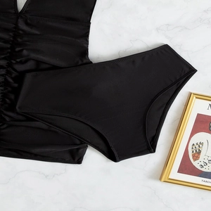 Chic black two-piece swimsuit set with high-waisted bottoms on marble background