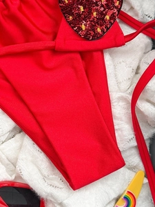 Dettaglio macro bikini rosso con cuore di paillettes su sfondo di pizzo bianco