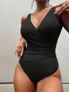 Close-up of black one-piece swimsuit featuring deep V-neck and metal ring wrap detail