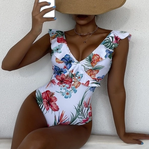 Detail view of ruffled deep V-neckline on one-piece swimsuit with tropical floral print