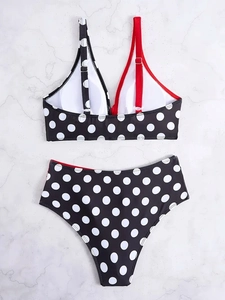 Flat lay of high waisted bikini set with polka dot print and asymmetrical red strap