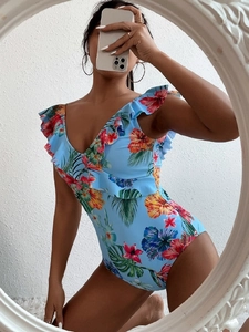 Detail of floral one-piece swimsuit with ruffled neckline and tropical palm leaf print