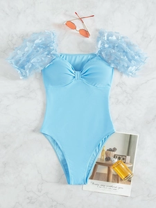 Flat lay of light blue one-piece swimsuit with butterfly mesh puff sleeves and sunglasses