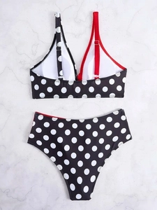 Polka dot high waisted bikini set with red asymmetrical strap on marble background