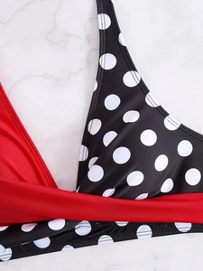 Red and black polka dot high waist bikini top with V-neck cross design on marble