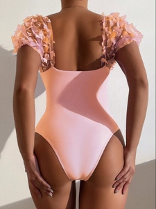 Detail of pink one-piece swimsuit featuring 3D butterfly appliques and deep U-back design