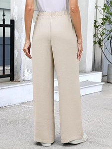 Detail view of beige high waisted wide leg trousers showing elastic waist and textured fabric