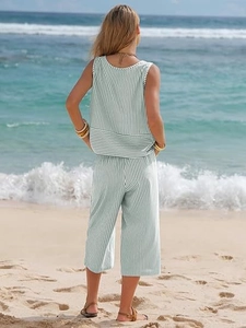 Rear view of women's green striped sleeveless top and wide leg pants set on a sunny beach