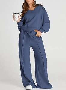 Detail of dark blue V-neck sweatshirt and wide-leg trousers with vertical pleats