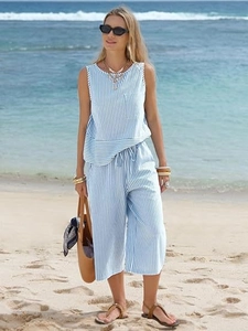 Outdoor shot of a women's blue and white striped summer two-piece sleeveless set with pants
