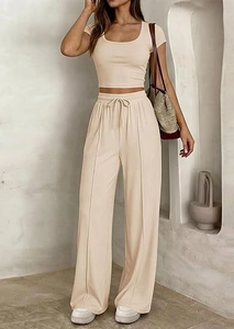 Dettaglio dei pantaloni beige a gamba larga con vita alta, coulisse e cucitura frontale