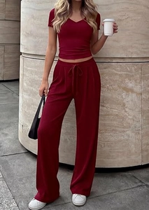 Detail of burgundy rib-knit V-neck top and matching wide-leg pants set in outdoor setting