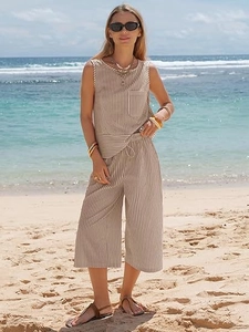 Detail of striped sleeveless top and wide-leg trousers set against a beach backdrop