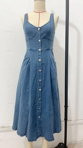 Détail d'une robe midi en jean bleu avec boutons métalliques et coupe trapèze ajustée