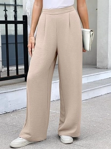 Detail of high-waisted wide-leg trousers in beige with premium textured pleated fabric