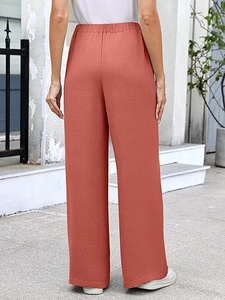 Rear view of rust red wide leg trousers featuring elastic waist and textured fabric detail
