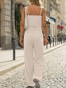 Back view of a woman wearing a chic cream two-piece lounge set with camisole and wide-leg pants