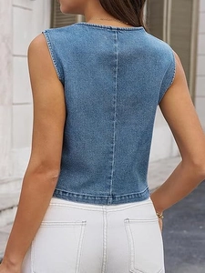 Detail of the back view of a blue denim vest with central seam and wash texture