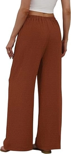 Detail view of high-waist elastic waistband and textured fabric on rust red wide-leg pants
