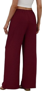 Close-up of burgundy wide-leg trousers featuring elastic waist and pleated fabric texture