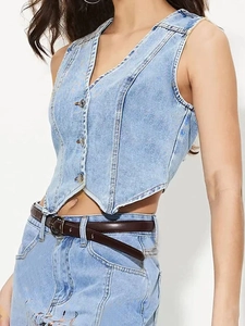 Détail du gilet en jean à col en V avec boutons métalliques et coupe d'ourlet irrégulière