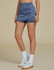 Detail of high waisted asymmetric wrap denim skort in retro wash blue style