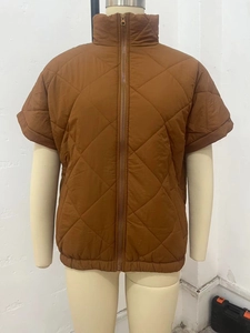 Detail of brown quilted puffer vest featuring high collar, full zipper and diamond stitching