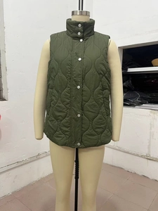 Detail of dark green quilted vest featuring silver snap buttons and wave stitching