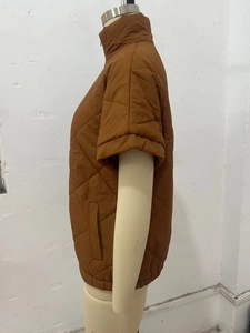 Detailed view of women's brown quilted vest with diamond pattern and elastic hem