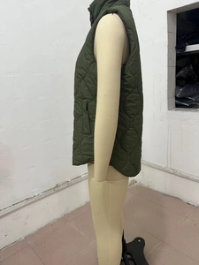 Detailed side view of dark green quilted vest with stand collar and pocket on mannequin