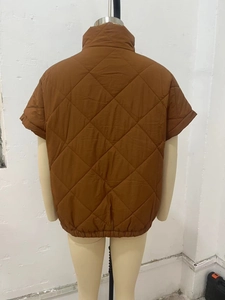 Detail of brown diamond-quilted vest showing stitching texture and stand collar