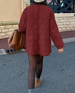 Back view of a woman in a burgundy quilted longline coat with unique gourd stitching