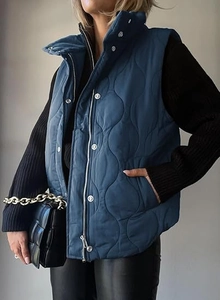 Detail of navy quilted vest featuring a stand collar, zipper, and snap button closure