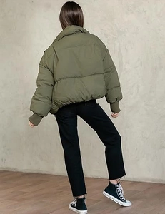 Rear view of an olive green oversized quilted puffer jacket with stand collar and ribbed cuffs