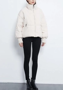 Detail of white puffer jacket with stand collar, zipper pockets, and elastic cuffs