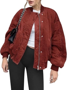 Detail of a wave-quilted brick red bomber jacket showing metal zipper and button closure